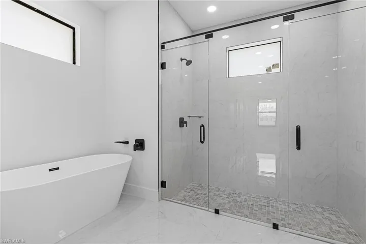 Full bathroom featuring a soaking tub, baseboards, marble finish floor, and a marble finish shower
