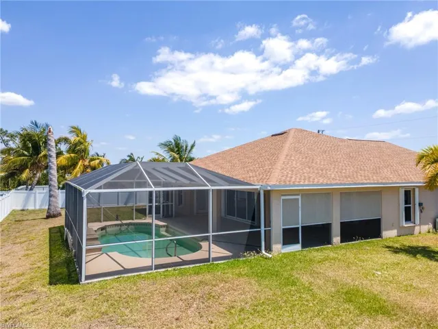 Rear view of property featuring a fenced in pool, a yard, stucco siding, and fence