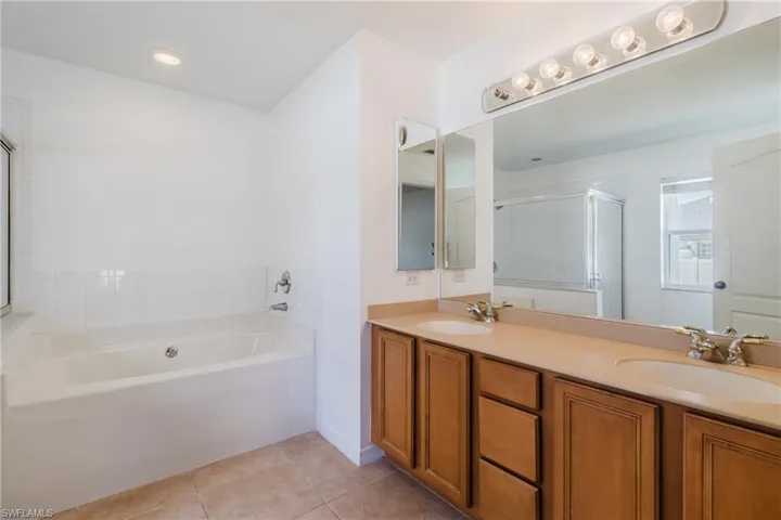Bathroom with a shower stall, tile patterned flooring, a bath, and a sink