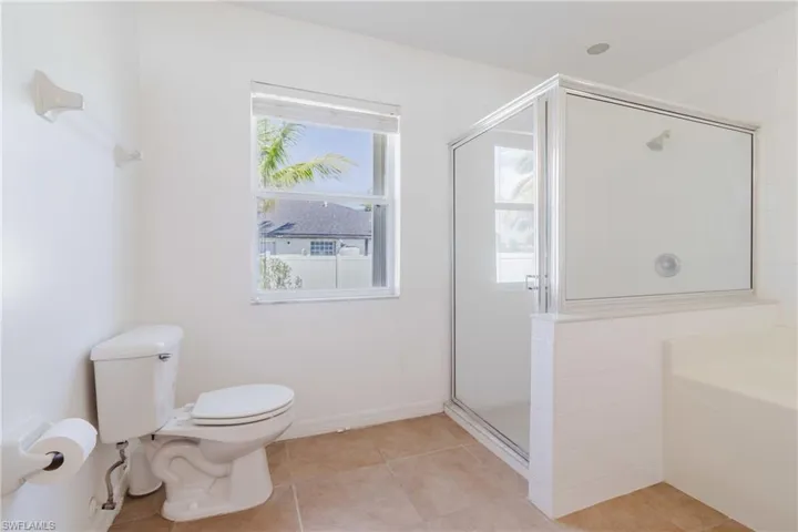 Bathroom with tile patterned floors, toilet, a stall shower, and a garden tub