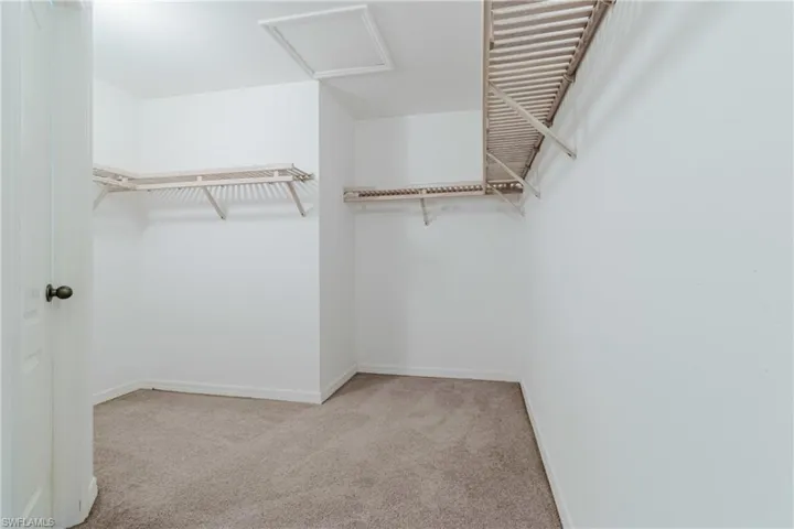 Walk in closet featuring attic access and carpet floors
