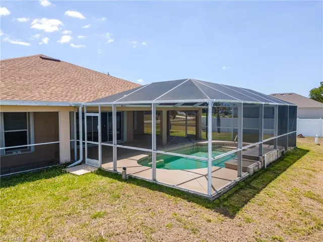 Back of property with a yard, fence, a patio, an outdoor pool, and a lanai