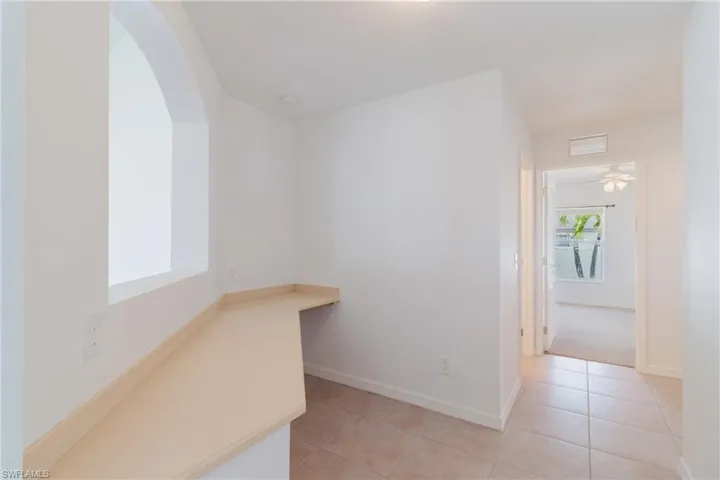 Hallway featuring arched walkways, light tile patterned floors, baseboards, and visible vents