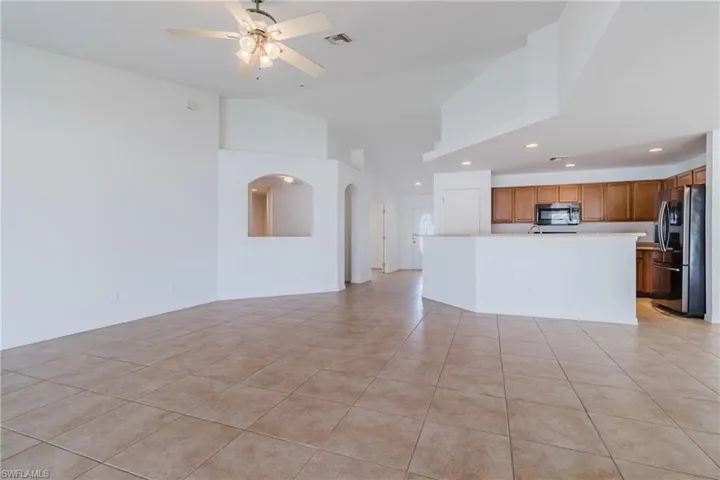 Unfurnished living room featuring recessed lighting, light tile patterned floors, visible vents, ceiling fan, and arched walkways