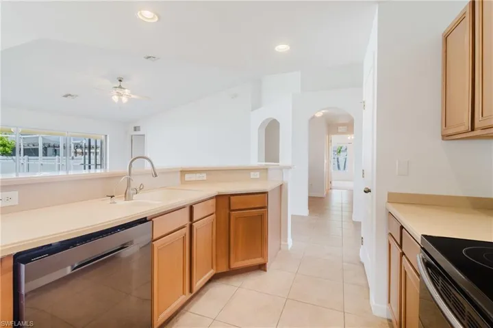 Kitchen with ceiling fan, light tile patterned flooring, dishwasher, a sink, and light countertops