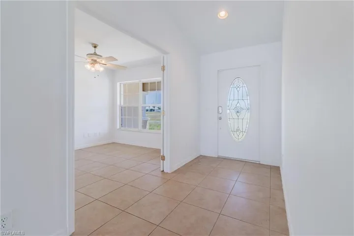 Foyer with light tile patterned floors, a ceiling fan, and plenty of natural light