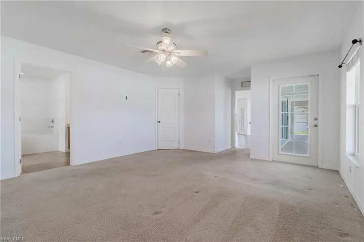 Carpeted spare room with baseboards, a ceiling fan, and plenty of natural light