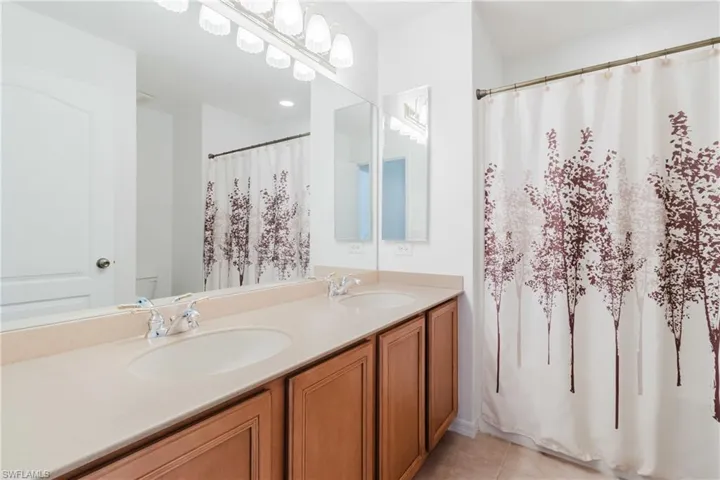 Bathroom featuring a sink, tile patterned floors, double vanity, and toilet