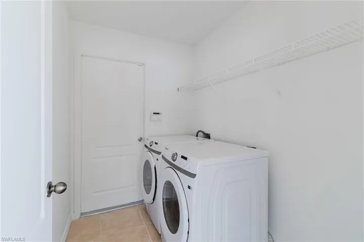 Washroom featuring baseboards, separate washer and dryer, laundry area, and light tile patterned flooring