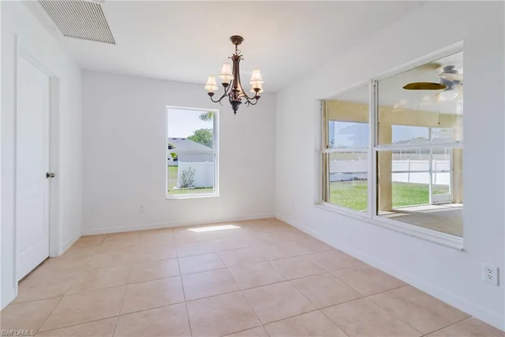 Spare room with a chandelier, light tile patterned floors, baseboards, and visible vents