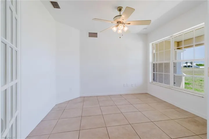 Empty room with visible vents, baseboards, light tile patterned flooring, and ceiling fan