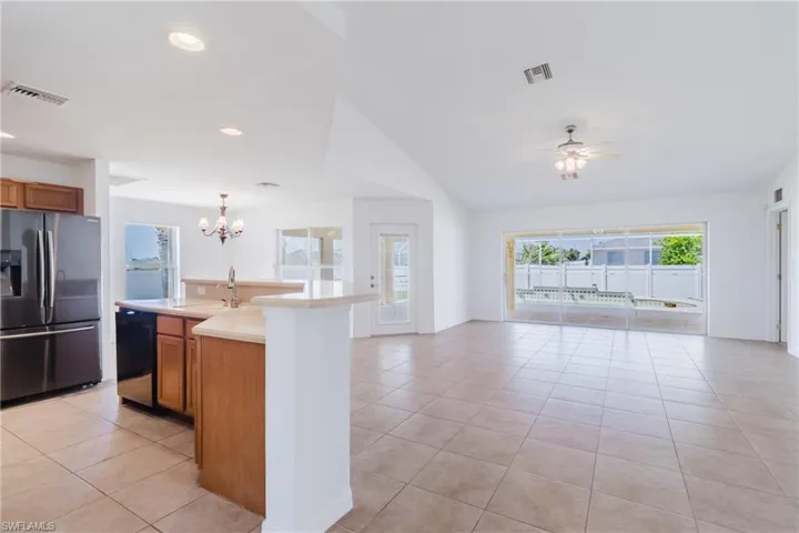 Kitchen featuring visible vents, dishwasher, stainless steel fridge, open floor plan, and brown cabinets