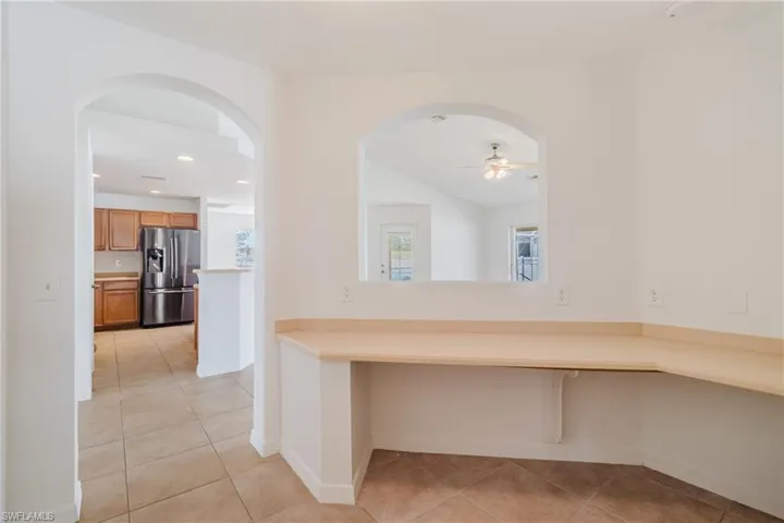 Corridor featuring recessed lighting, arched walkways, light tile patterned flooring, and lofted ceiling