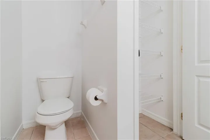 Bathroom with toilet, tile patterned floors, and baseboards
