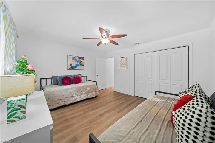 Spacious room featuring wood-finish flooring, white walls, and a ceiling fan with light