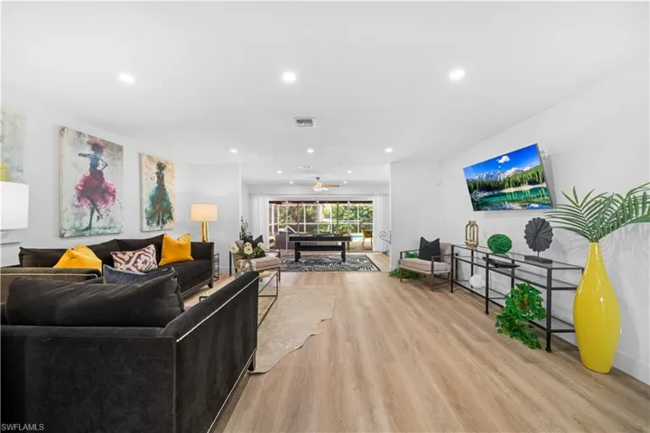 Open-concept living area with wood-finish flooring, recessed lighting, and white walls
