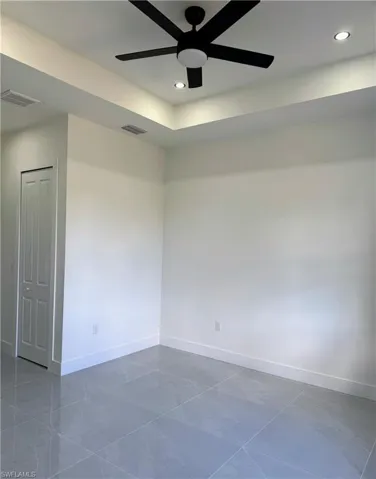 Tray ceiling with recessed lighting and a contemporary black ceiling fan