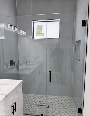 Modern shower enclosure featuring a clear glass door, hexagon-patterned floor tiling, and a linear drain