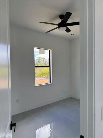 Room featuring a window with an outdoor landscape, a black ceiling fan, recessed lighting, and grey tile flooring