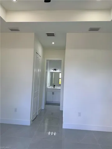 Polished tile flooring extending into a bathroom with a white vanity and wall-mounted mirror
