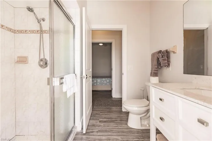 Bathroom featuring an enclosed shower, hardwood / wood-style flooring, large vanity, and toilet