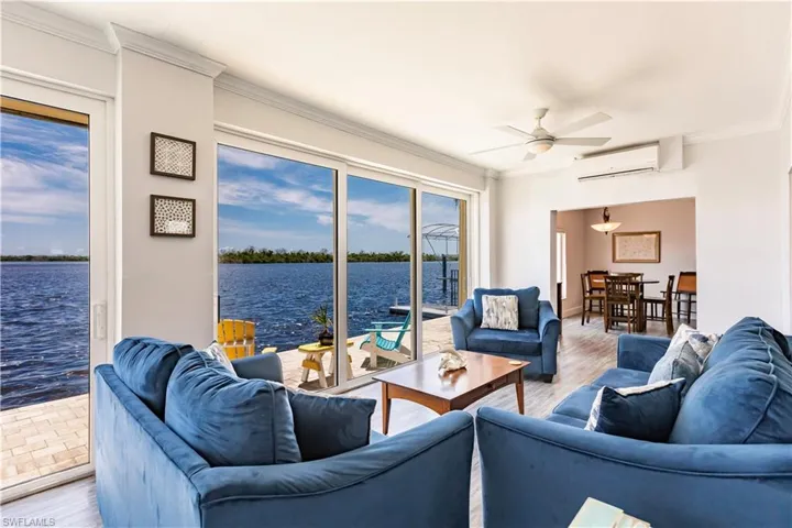 Living room with a water view, ceiling fan, hardwood / wood-style flooring, and an AC wall unit