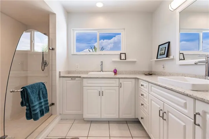Bathroom with tile floors, dual sinks, oversized vanity, and a shower