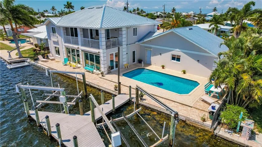 View of swimming pool with a patio, a water view, and a dock