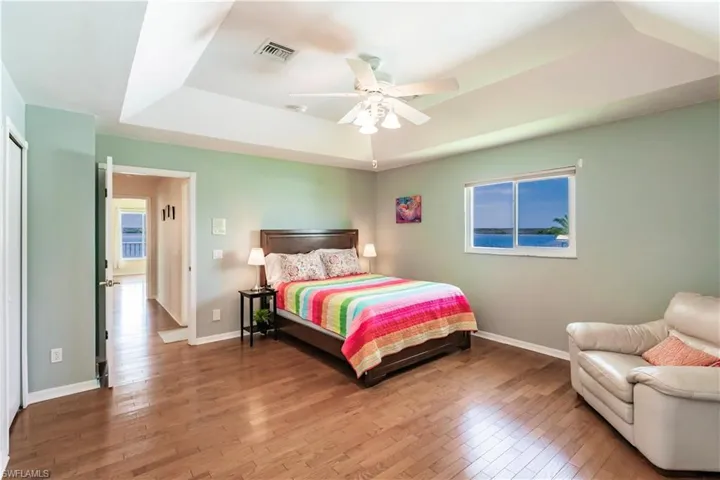 Bedroom featuring hardwood / wood-style floors, ceiling fan, and a raised ceiling