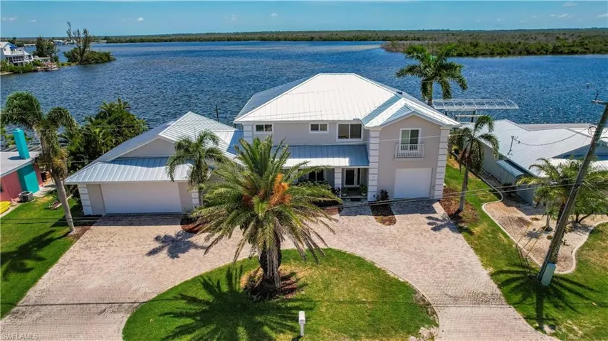 View of front of property with a front yard, a garage, and a water view