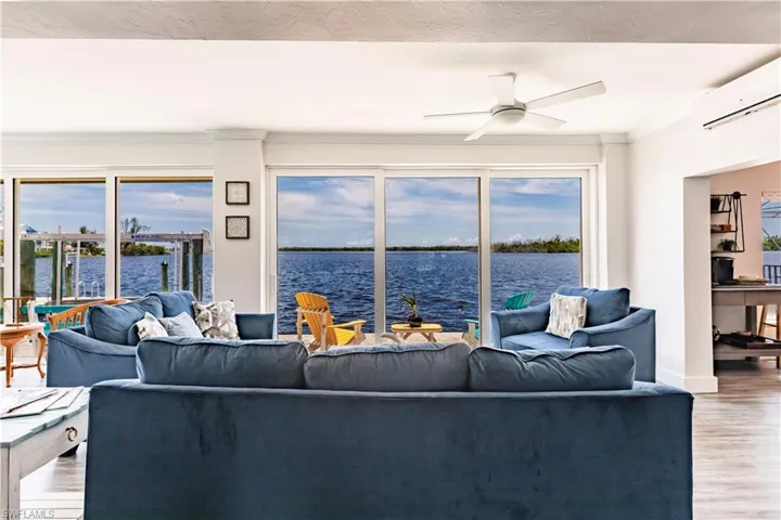 Living room with wood-type flooring, a water view, ceiling fan, and a wall mounted AC