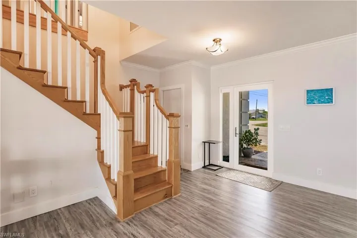 Foyer with ornamental molding and hardwood / wood-style floors