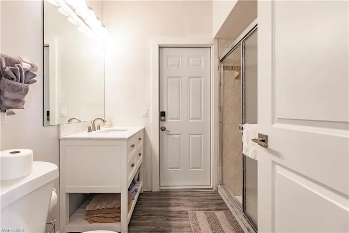 Bathroom featuring an enclosed shower, hardwood / wood-style flooring, large vanity, and toilet