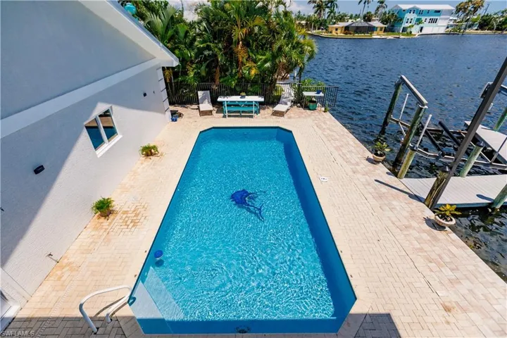 View of swimming pool with a patio, a water view, and a dock
