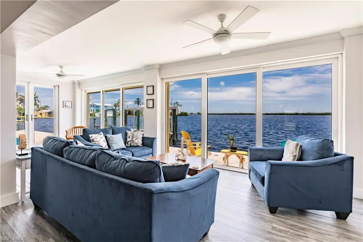 Living room featuring crown molding, hardwood / wood-style flooring, ceiling fan, and a water view