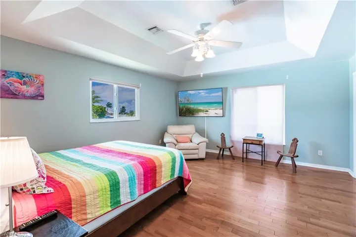Bedroom featuring hardwood / wood-style floors, ceiling fan, and a raised ceiling