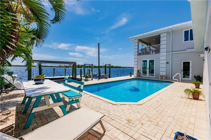 View of swimming pool featuring a water view, french doors, and a patio area