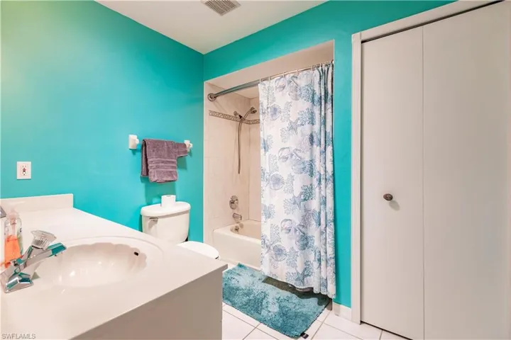 Full bathroom with tile floors, vanity, toilet, and shower / bath combo with shower curtain