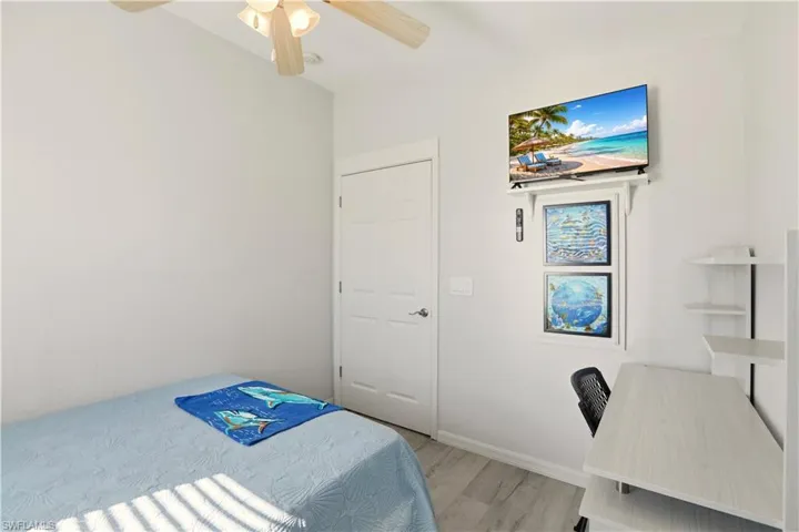 Bedroom with a desk, light wood-style floors, and a ceiling fan