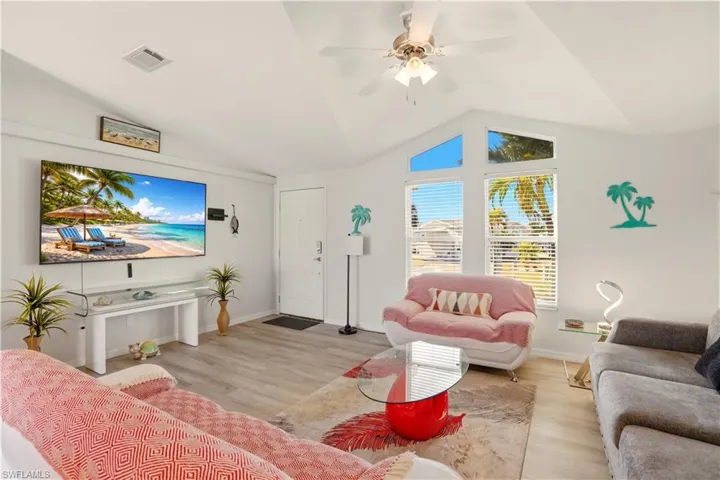 Living area featuring ceiling fan, wood finished floors, and vaulted ceiling