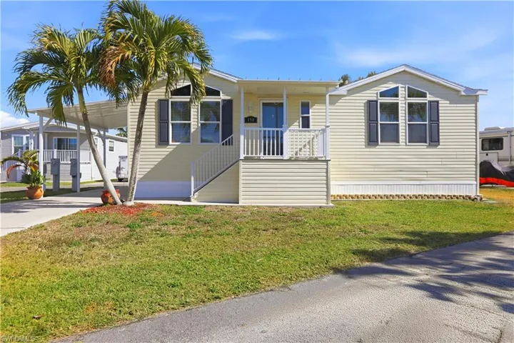 Manufactured / mobile home featuring covered porch, an attached carport, a front lawn, and driveway