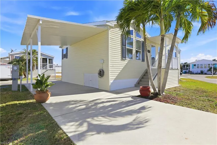 View of side of home featuring an attached carport, driveway, and a yard