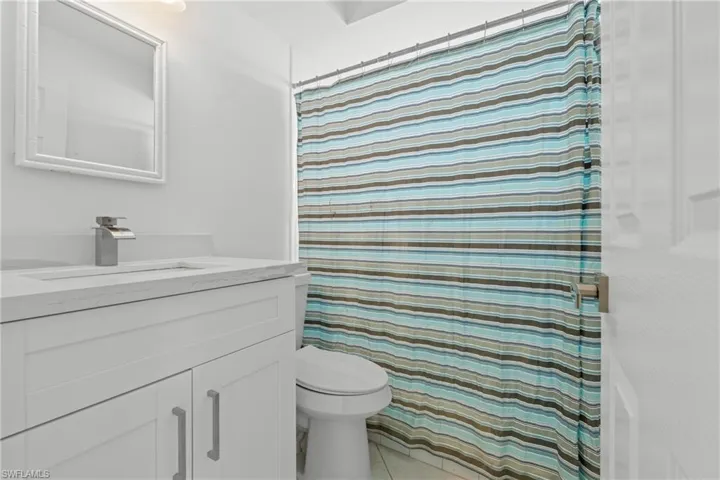 Full bathroom with curtained shower, vanity, and light tile patterned flooring