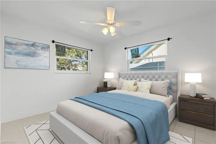 (Virtually Staged) Bedroom with light tile patterned floors, ceiling fan, and multiple windows