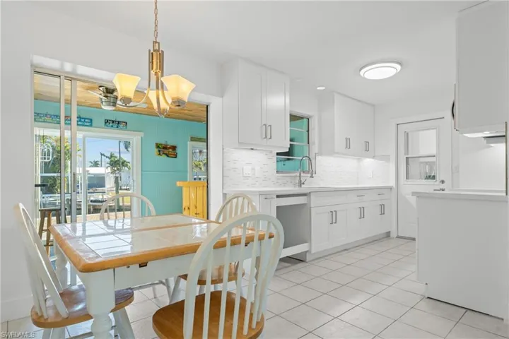 Kitchen with white cabinetry, tasteful backsplash, pendant lighting, light tile patterned flooring, and a chandelier