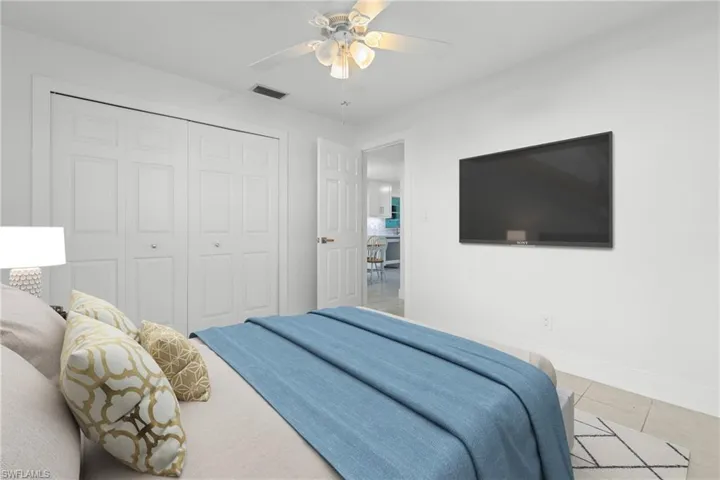 (Virtually Staged) Tiled bedroom with a ceiling fan and a closet