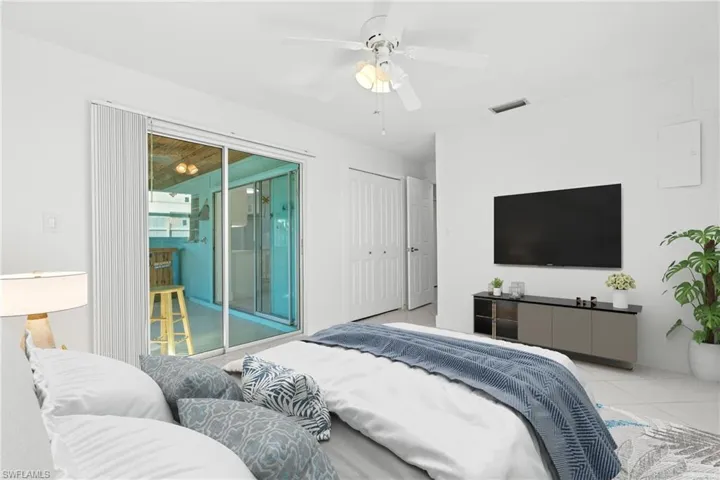 (Virtually Staged) Bedroom featuring a ceiling fan, light tile patterned floors, access to exterior, and a closet