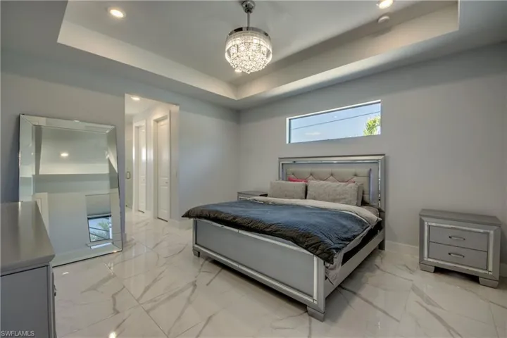 Bedroom with recessed lighting, marble finish floor, baseboards, a raised ceiling, and a notable chandelier