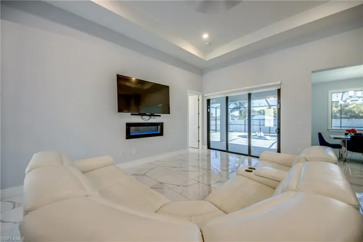 Living room featuring a glass covered fireplace, recessed lighting, marble finish floor, and baseboards