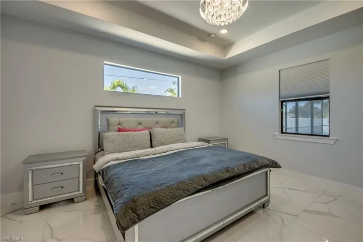 Bedroom with baseboards, multiple windows, and marble finish floor
